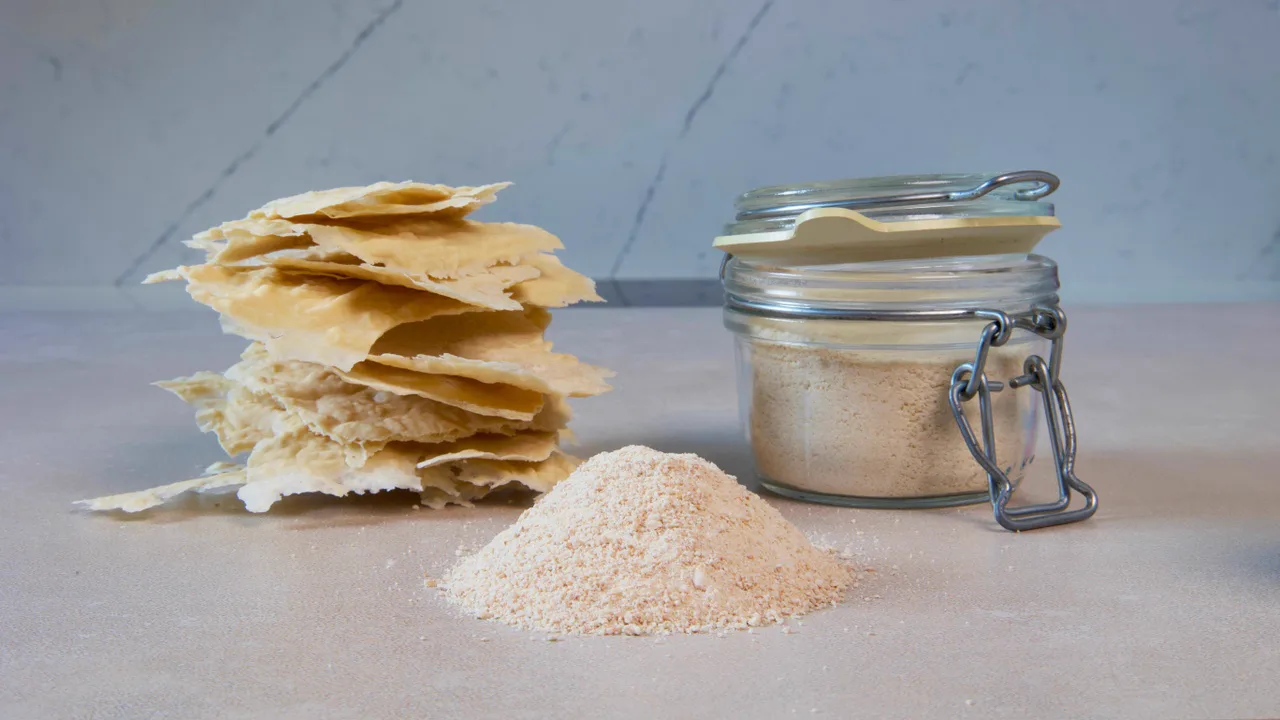 Dried sourdough starter flakes beside powdered dried starter and a labeled storage jar